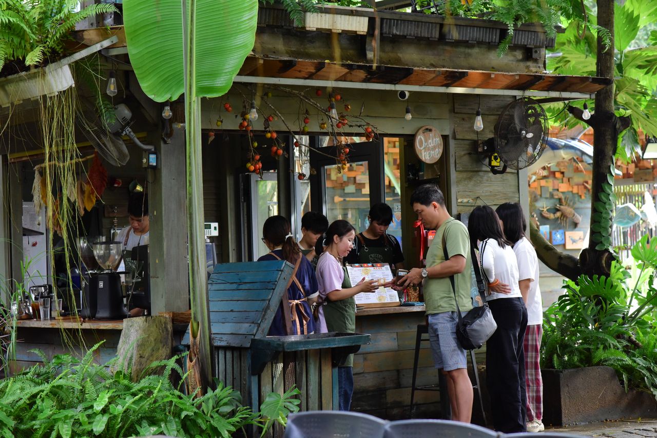 Crafting Captivating Headlines: Your awesome post title goes here A small group of people gathered at an outdoor coffee shop in a verdant, tropical setting.